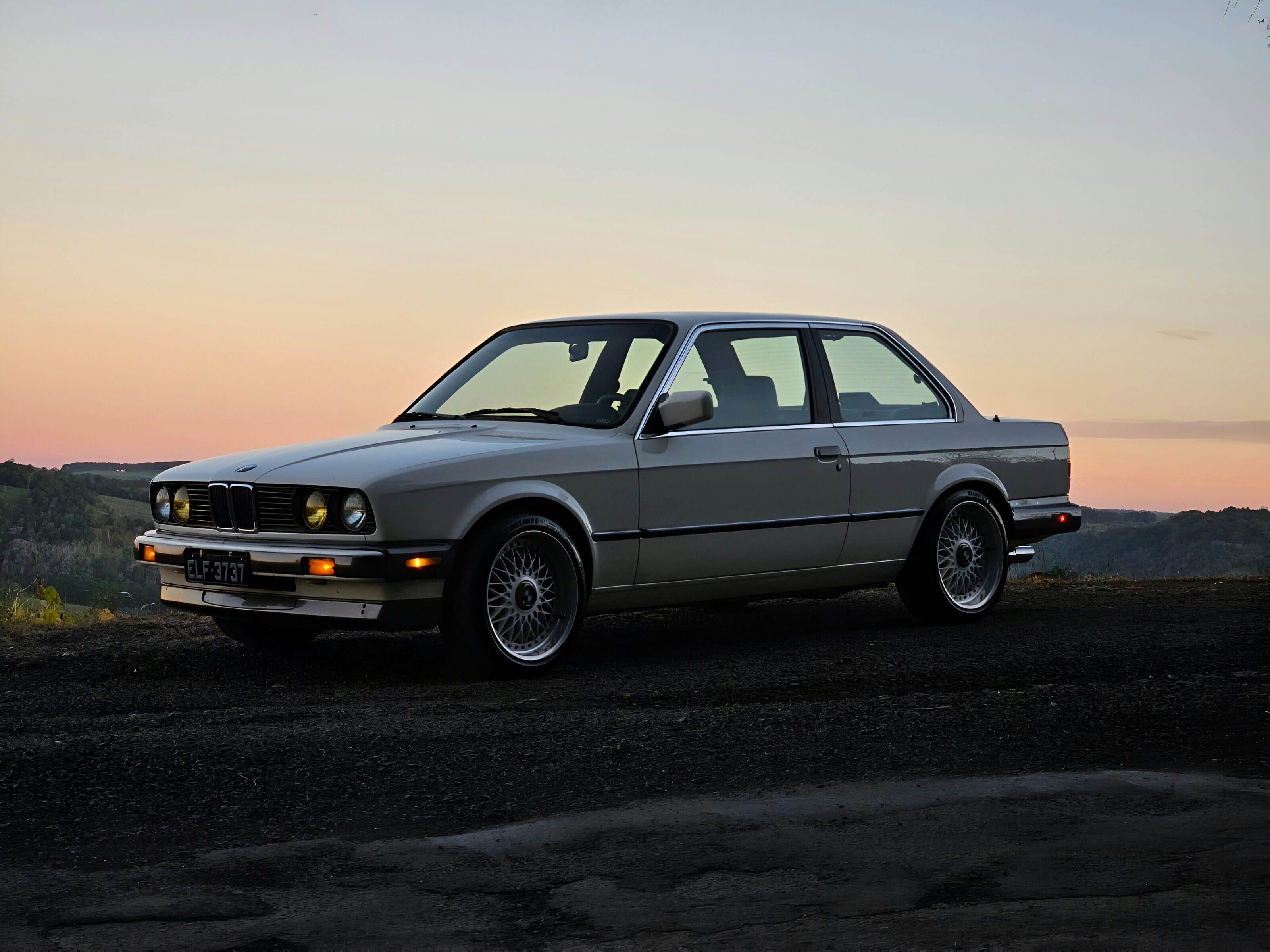 A classic BMW coupe parked at sunset